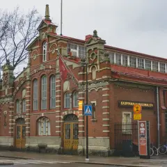 Ceglana hala targowa w Turku, dawnej stolicy Finlandii, z charakterystycznymi łukami i flagami.