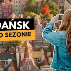 Dziewczyna robi zdjęcie jesiennego Gdańska. W tle kolorowe kamienice i liście.