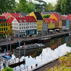 Kolorowe kamienice nad kanałem w miniaturowym Legolandzie Kopenhaga, z odbiciem w wodzie.
