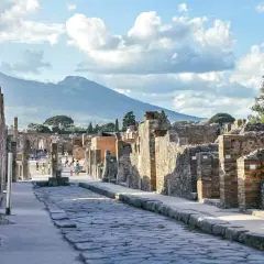 Starożytna droga w Pompejach, z Wezuwiuszem w tle. Idealne miejsce, by poczuć historię i zastanowić się, jak dojechać z Neapolu do Pompejów.