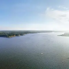 Spokojne jezioro w Lublinie Zemborzycach, otoczone lasem, z żaglówkami i pomostem.