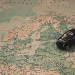 Czarny samochodzik na mapie Europy, szukający drogi do Mikołajek.