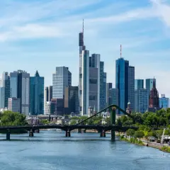 Widok na nowoczesną panoramę miasta z rzeką i mostem. Widać wieżowce, które jasno wskazują, gdzie jest Frankfurt.