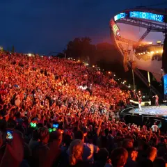 Tłumy rozbawionych ludzi na mrągowo festiwal, oświetlone sceną i kolorowymi światełkami.