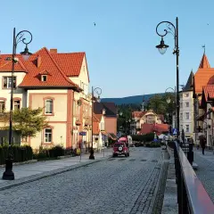 Urokliwa ulica w Świeradowie-Zdroju, z kamienną nawierzchnią i zabytkowymi kamienicami. Idealne miejsce na spacer po uzdrowisku, które przypomina krajobraz z Jeleniej Góry.