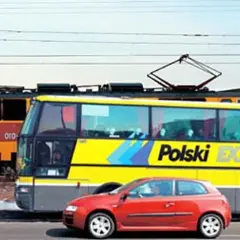 Pociąg i żółty autobus "Polski Express" jadą obok siebie. Czerwony samochód na pierwszym planie. Podróż z Poznania do Lublina?