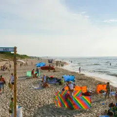 Słoneczny dzień na plaży w Łazach pod Warszawą. Ludzie odpoczywają, bawią się i kąpią w morzu.