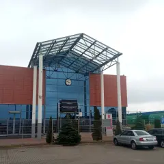 Nowoczesny budynek dworca kolejowego z przeszklonym dachem i zegarem.