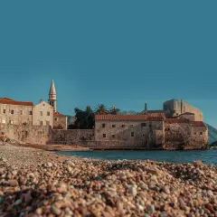 Kamienista plaża w Budvie, z widokiem na starówkę i morze. Idealne miejsce na odpoczynek po podróży, nawet jeśli lotnisko jest daleko.