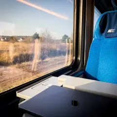 Widok z okna pociągu PKP, kiedy zmiana rozkładu jazdy PKP zaskoczyła pasażerów. Siedzenie w pociągu i krajobraz za oknem.