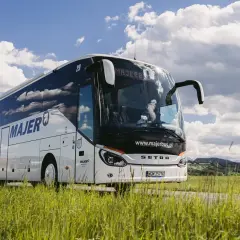 Autobus Majer na trasie Kraków-Mszana, podróż przez zielone pola pod błękitnym niebem.