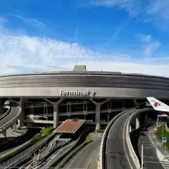 Terminal 1 lotniska BVA Paris, z charakterystycznym, okrągłym kształtem i drogami prowadzącymi do niego. Widoczny fragment skrzydła samolotu Qatar Airways.