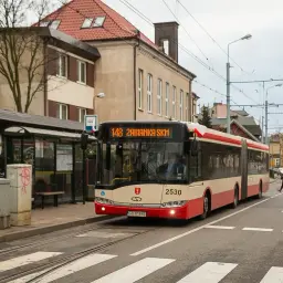 Autobus linii 148 zbliża się do przystanki autobusowe w mieście. Kobieta przechodzi przez pasy.