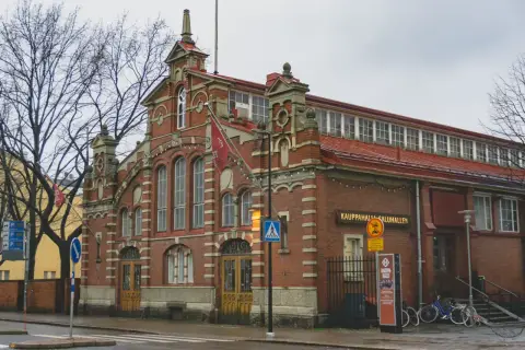 Ceglana hala targowa w Turku, dawnej stolicy Finlandii, z charakterystycznymi łukami i flagami.