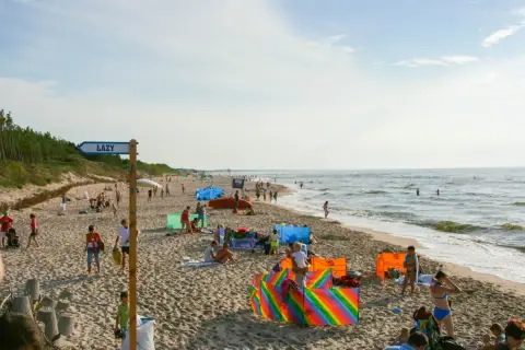 Słoneczny dzień na plaży w Łazach pod Warszawą. Ludzie odpoczywają, bawią się i kąpią w morzu.