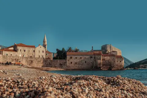 Kamienista plaża w Budvie, z widokiem na starówkę i morze. Idealne miejsce na odpoczynek po podróży, nawet jeśli lotnisko jest daleko.