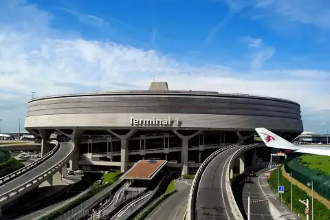 Terminal 1 lotniska BVA Paris, z charakterystycznym, okrągłym kształtem i drogami prowadzącymi do niego. Widoczny fragment skrzydła samolotu Qatar Airways.
