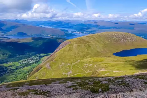 Widok z najwyższego szczytu Wielkiej Brytanii, Ben Nevis, na malownicze jezioro i górzysty krajobraz Szkocji.