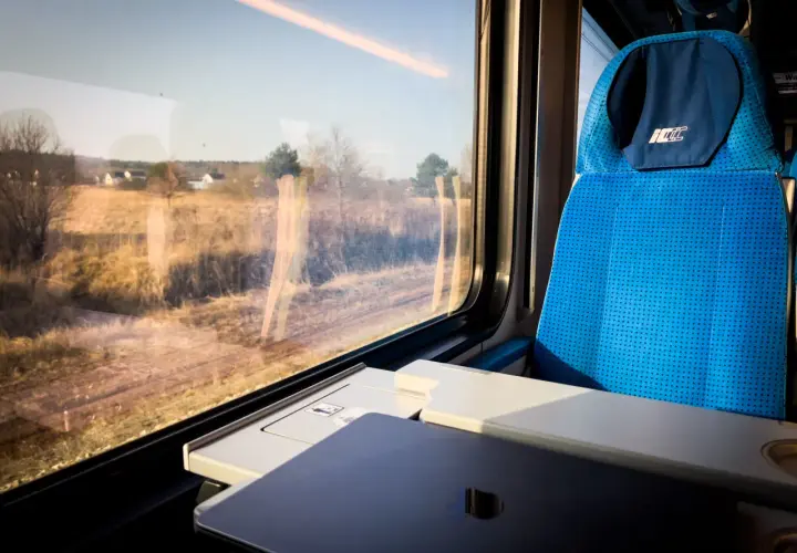 Widok z okna pociągu PKP, kiedy zmiana rozkładu jazdy PKP zaskoczyła pasażerów. Siedzenie w pociągu i krajobraz za oknem.