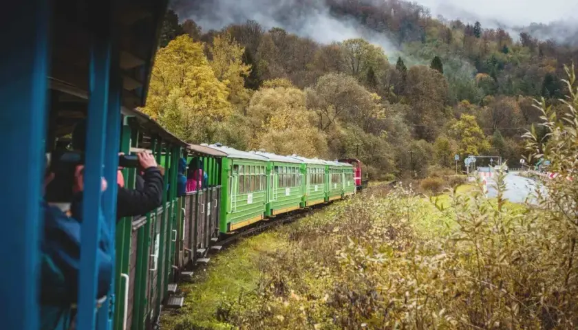 Zielony pociąg turystyczny mknie przez jesienne Bieszczady, w drodze z Krakowa do Soliny. Mgła spowija wzgórza.