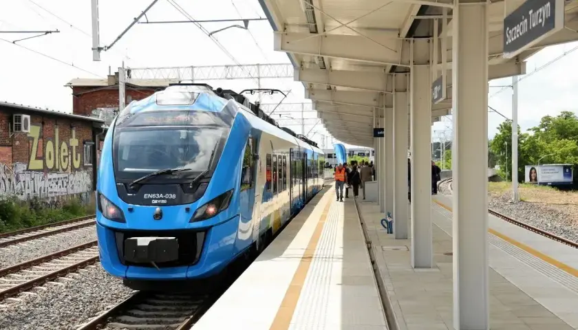 Błękitny pociąg EN63A-038 na stacji Szczecin Turzyn. Ludzie czekają na peronie, gotowi do podróży, być może do Łodzi.