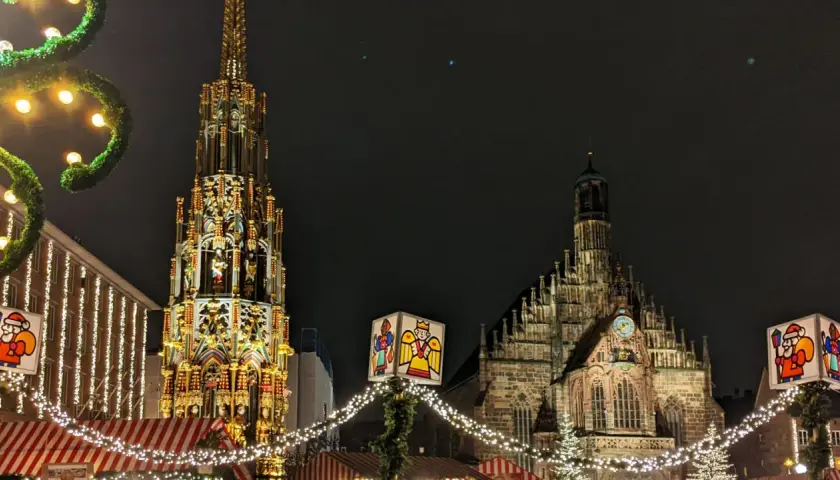 Nocne jarmarki bożonarodzeniowe w Europie. Wspaniała iluminacja zabytkowej fontanny i kościoła, ozdobione świątecznymi lampkami i dekoracjami.