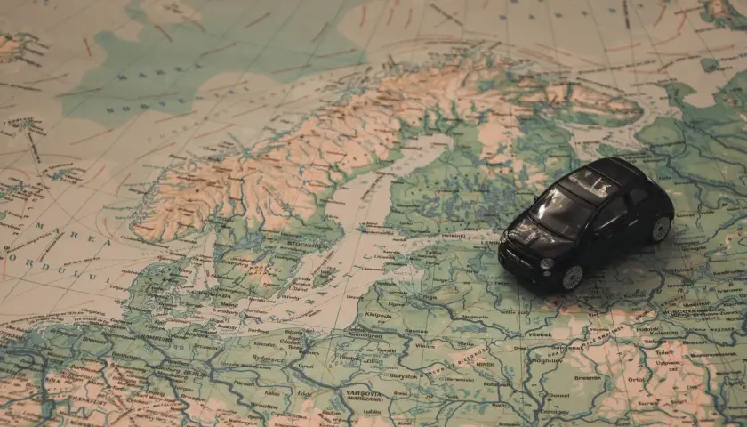 Czarny samochodzik na mapie Europy, szukający drogi do Mikołajek.