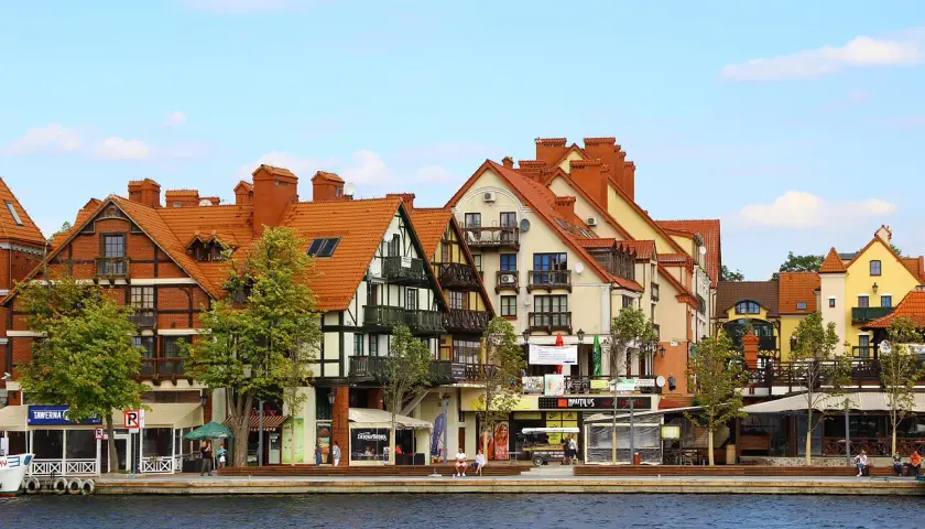 Urokliwa nadmorska promenada z kolorowymi kamieniczkami, jak z bajki o Mikołajkach w Warszawie.