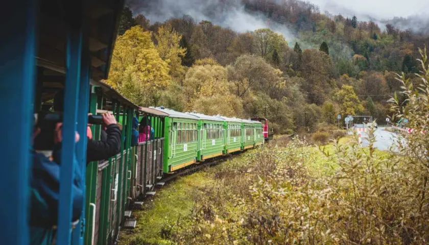 Zielony pociąg turystyczny mknie przez jesienne Bieszczady, zabierając pasażerów z Krakowa na malowniczą podróż.