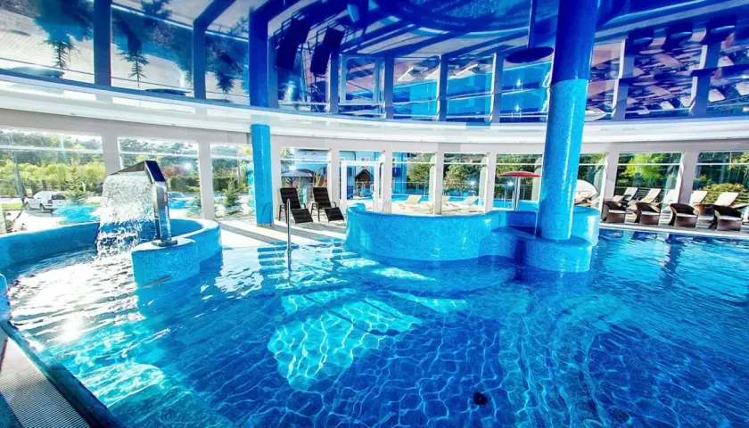 Relaks w nowoczesnych termach nad morzem bałtyckim. Błękitna woda, wodospad i leżaki zapraszają do odpoczynku.