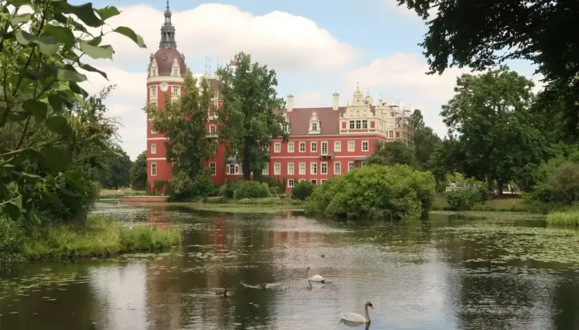 Zamek w Mużakowie zachwyca czerwienią i wieżą. Wokół jezioro z łabędziami, idealne miejsce na zwiedzanie.