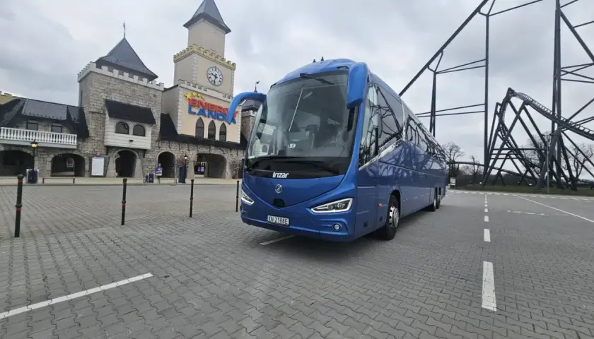 Niebieski autokar przed zamkiem w Energylandii, gotowy na wycieczkę z Wrocławia.