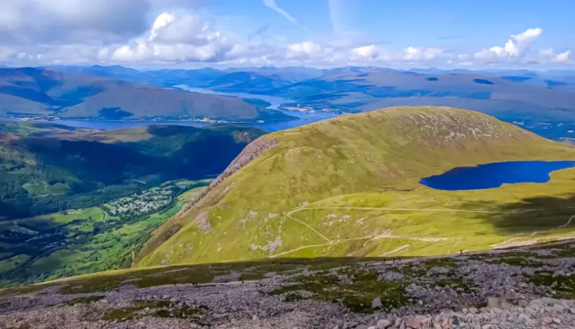Widok z najwyższego szczytu Wielkiej Brytanii, Ben Nevis, na malownicze jezioro i górzysty krajobraz Szkocji.