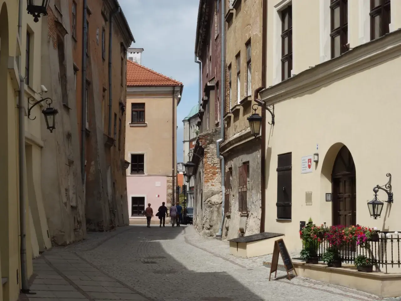 Spacer po urokliwej uliczce, jakbyśmy podróżowali między Białymstokiem a Lublinem. Kamienne budynki, latarnie i kwiaty tworzą niepowtarzalny klimat.