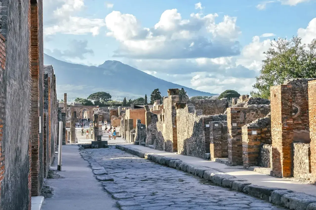 Starożytna droga w Pompejach, z Wezuwiuszem w tle. Idealne miejsce, by poczuć historię i zastanowić się, jak dojechać z Neapolu do Pompejów.
