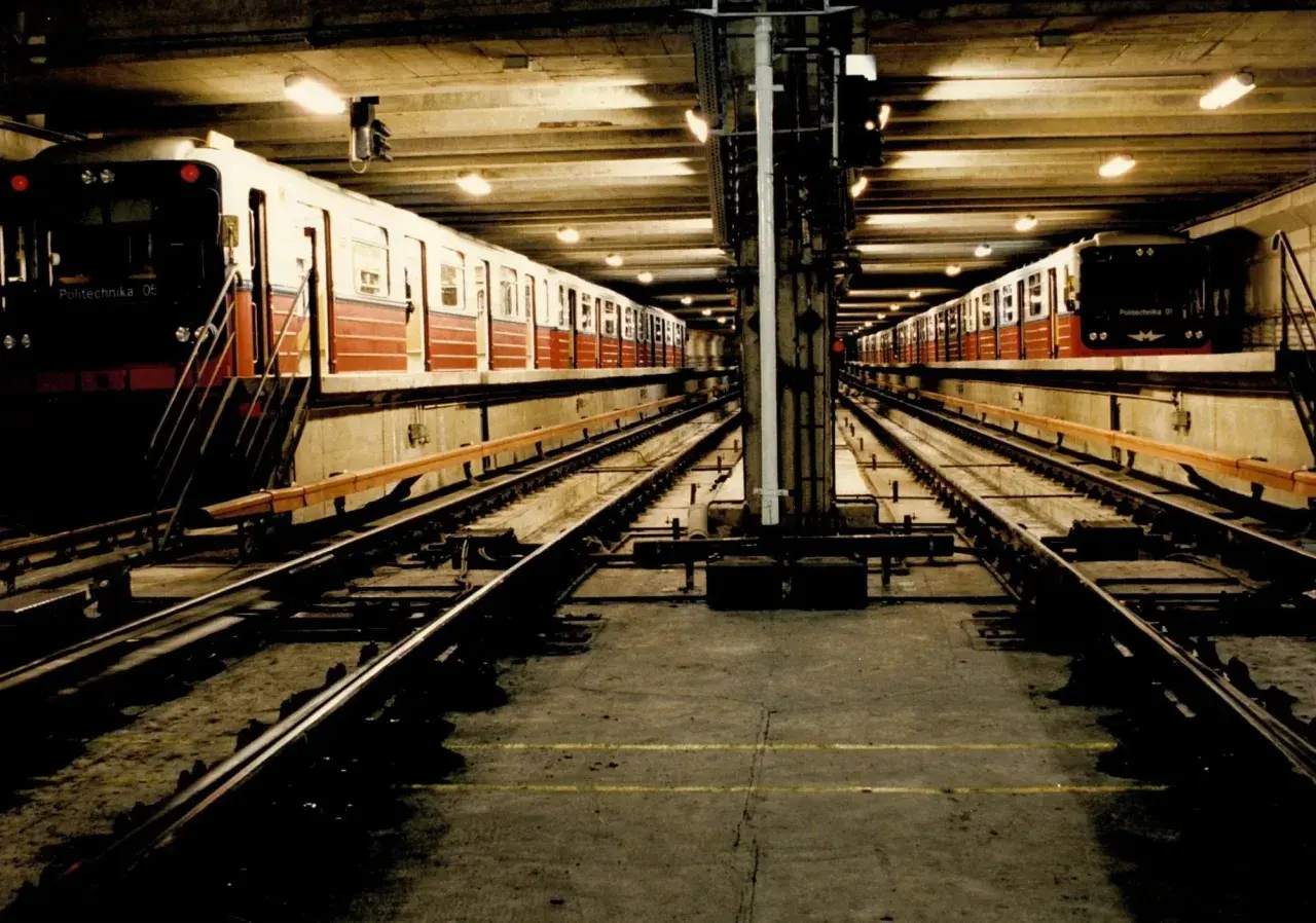 Dwa pociągi stoją na torach w podziemnej stacji metra M1.