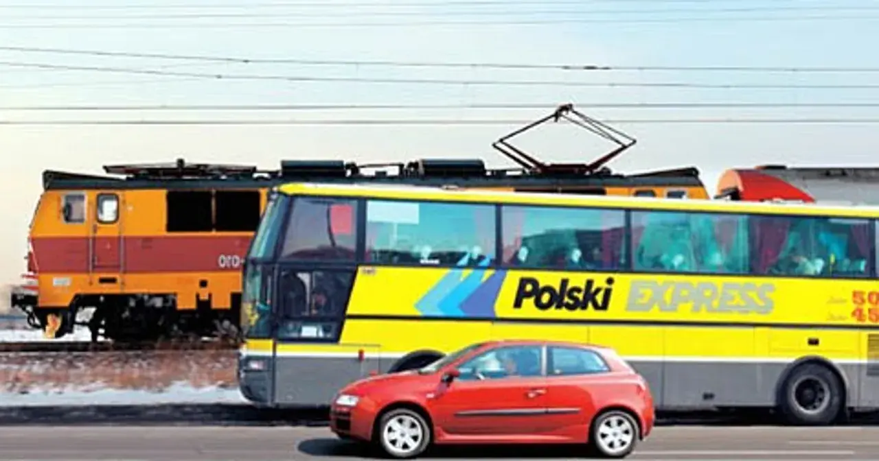 Pociąg i żółty autobus "Polski Express" jadą obok siebie. Czerwony samochód na pierwszym planie. Podróż z Poznania do Lublina?