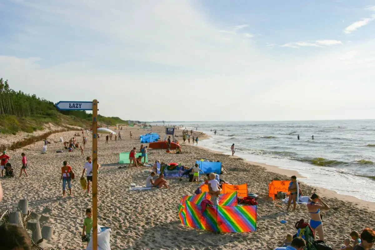 Słoneczny dzień na plaży w Łazach pod Warszawą. Ludzie odpoczywają, bawią się i kąpią w morzu.