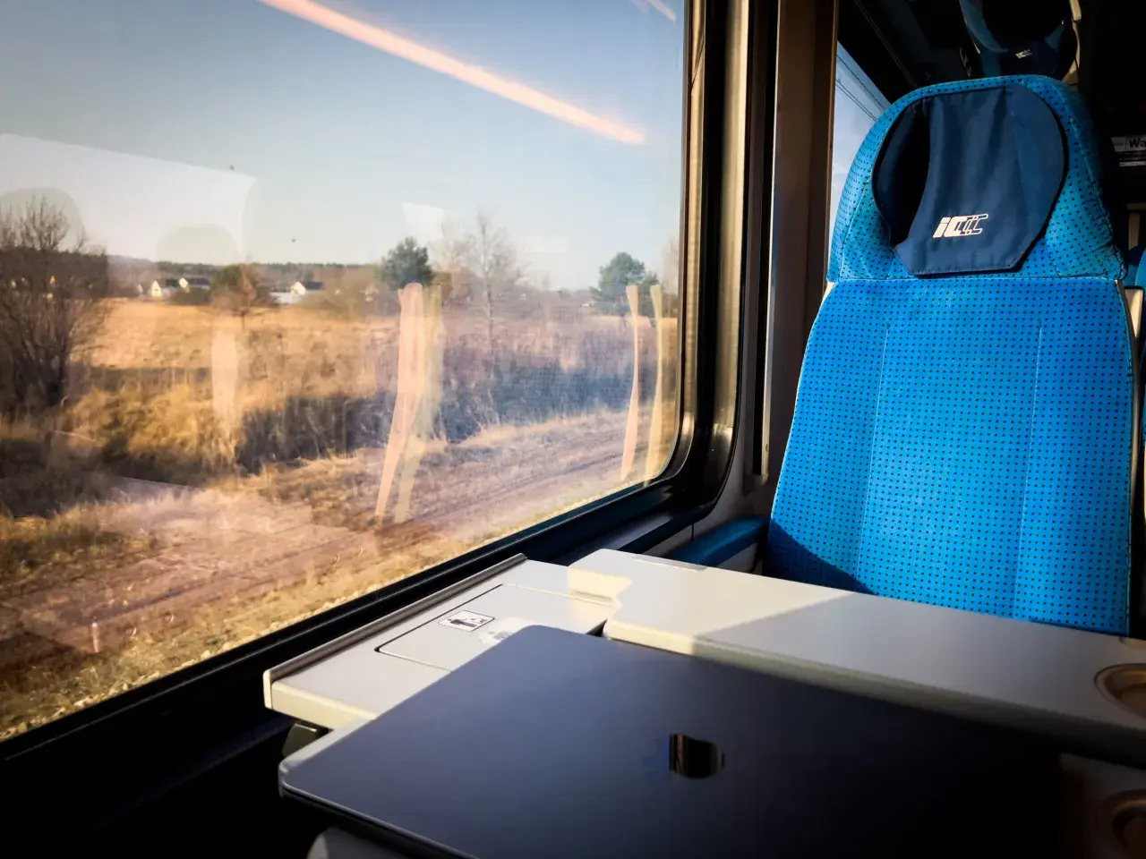 Widok z okna pociągu PKP, kiedy zmiana rozkładu jazdy PKP zaskoczyła pasażerów. Siedzenie w pociągu i krajobraz za oknem.