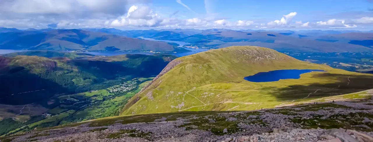 Widok z najwyższego szczytu Wielkiej Brytanii, Ben Nevis, na malownicze jezioro i górzysty krajobraz Szkocji.