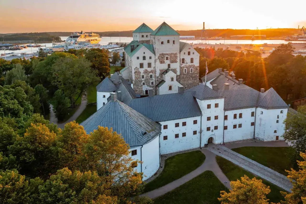 Zamek Olofsgård, dawna stolica Finlandii, w blasku zachodzącego słońca. W tle port z wycieczkowcem.