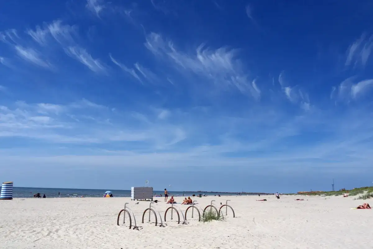 Piękny dzień nad łotewskim morzem. Piaszczysta plaża, błękitne niebo z delikatnymi chmurkami i kilka rowerów czekających na plażowiczów.