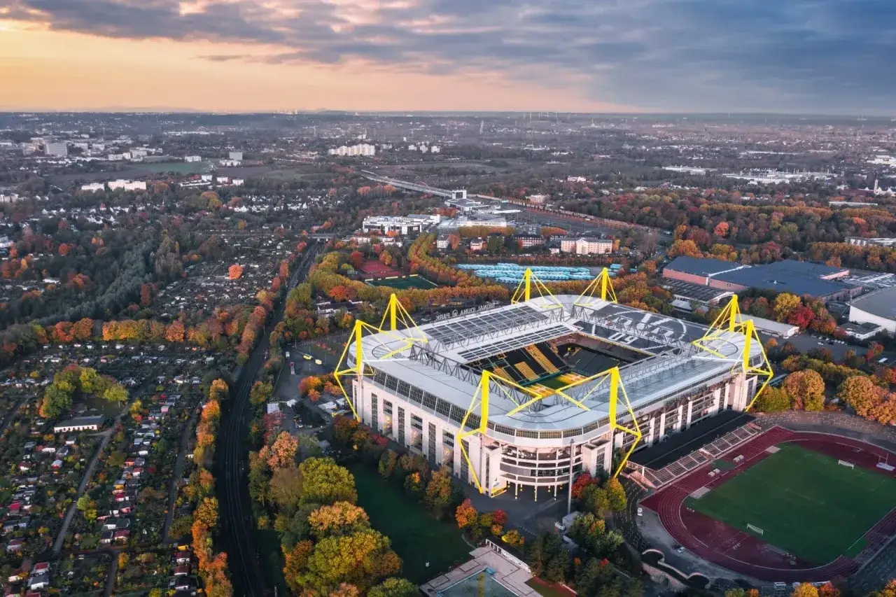 Widok z lotu ptaka na Signal Iduna Park, stadion w Dortmundzie, otoczony jesiennymi drzewami.