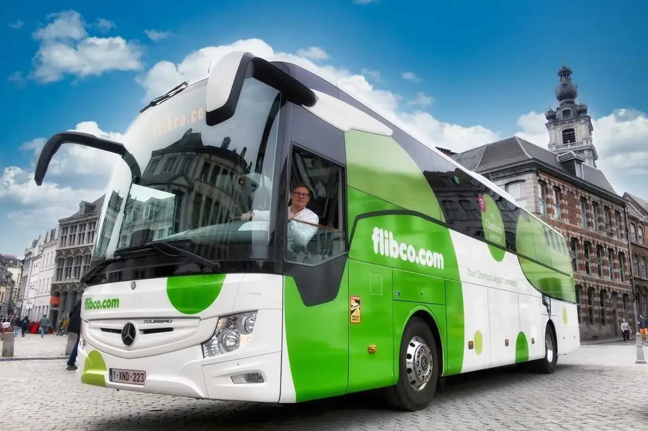 Bilet na autobus flibco.com z Bergamo do Mediolanu. Kierowca w okularach prowadzi zielono-biały autokar.