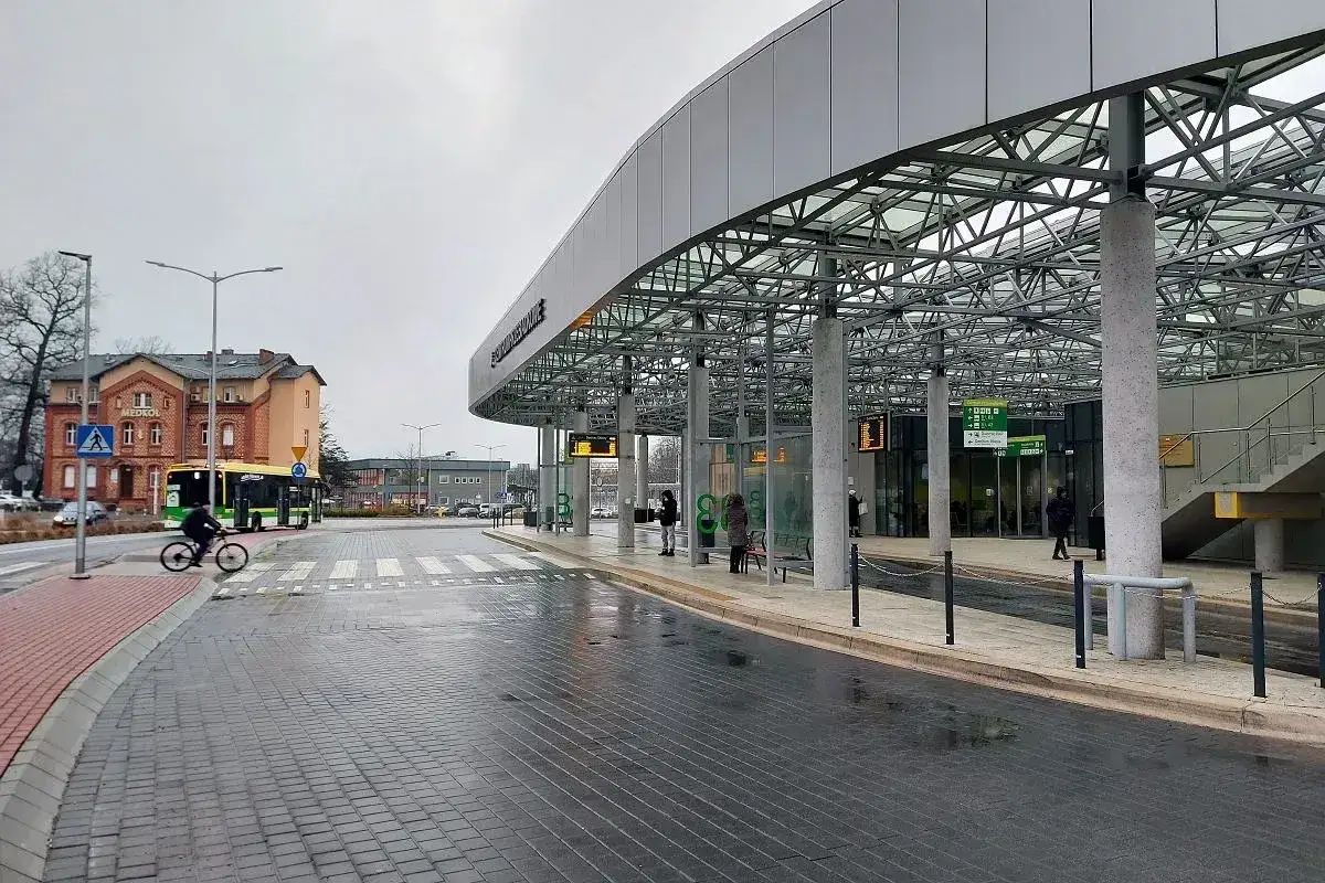 Nowoczesny dworzec autobusowy, gdzie busy przewozy po polsce czekają na pasażerów. W tle budynek z napisem 