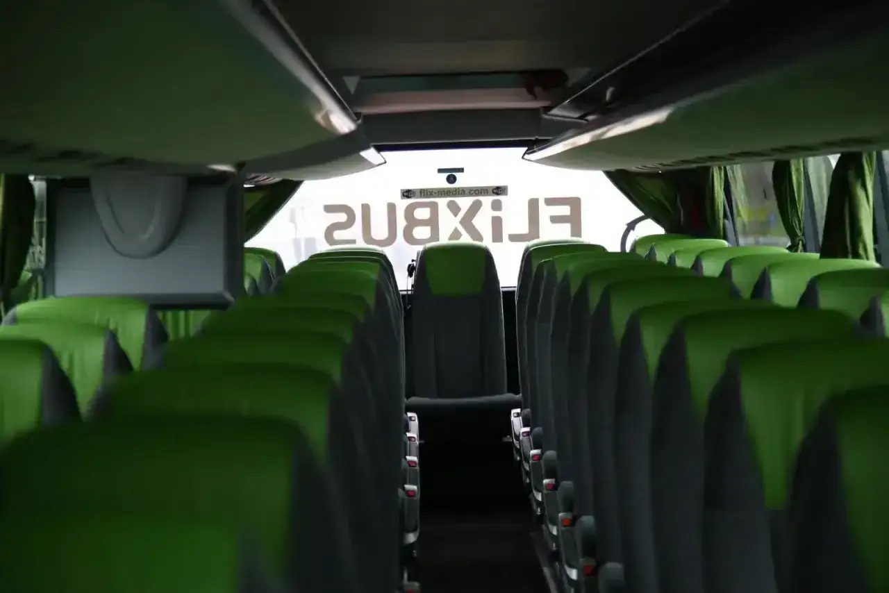 Widok z wnętrza autobusu Flixbus. Puste zielone siedzenia tworzą panoramiczny korytarz.